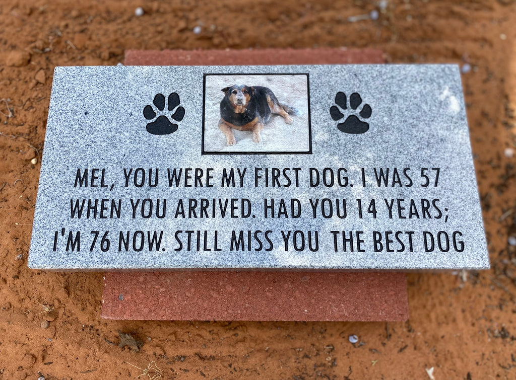Memorial plaque for a dog named Mel with text and paw prints on a brown surface.