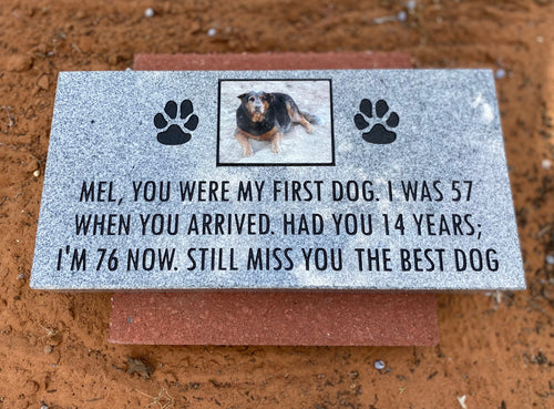 Memorial plaque for a dog named Mel with text and paw prints on a brown surface.